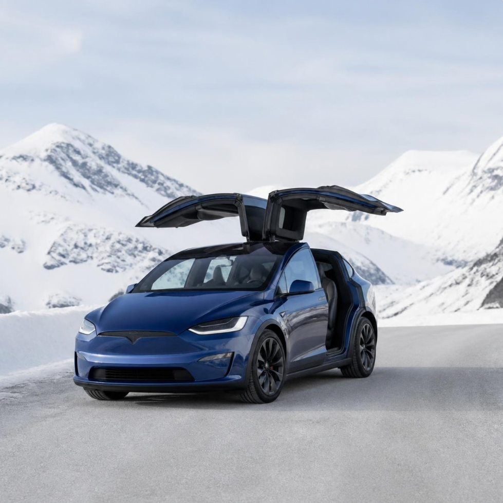 Blå Tesla Model X med åpne dører i fjellet